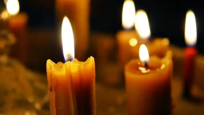 Antique candle burning in a dark room. Christmas Eve, divination, yuletide. Christmas backgrounds. holiday rituals, religion, spirituality, zen. space for text, close-up, copy space.