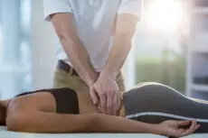 Male physiotherapist giving back massage to female patient in clinic
