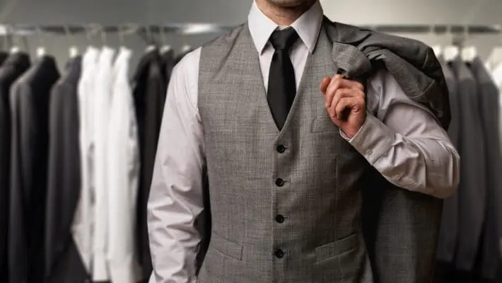 Businessman in classic vest against row of suits in shop