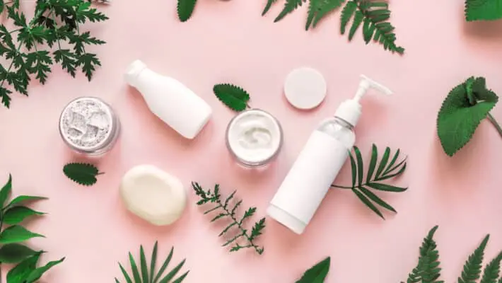 Natural,Cosmetics,And,Green,Leaves,On,Pink,Background,,Top,View,
