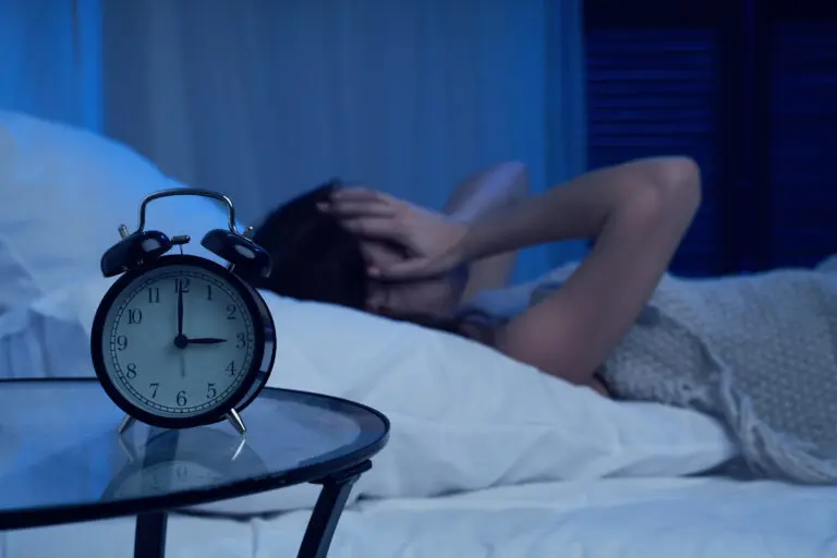 Unhappy,Woman,With,Insomnia,Lying,On,Bed,Next,To,Alarm
