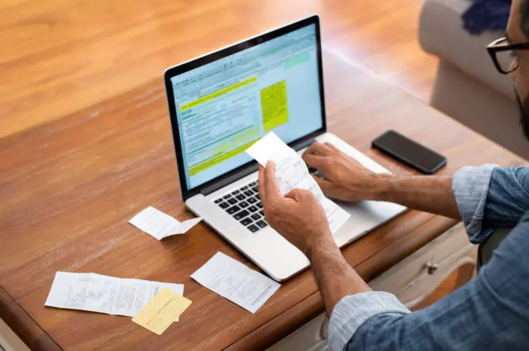 Hands,Of,Businessman,Analyzing,Invoice,On,Laptop,While,Checking,Bills.