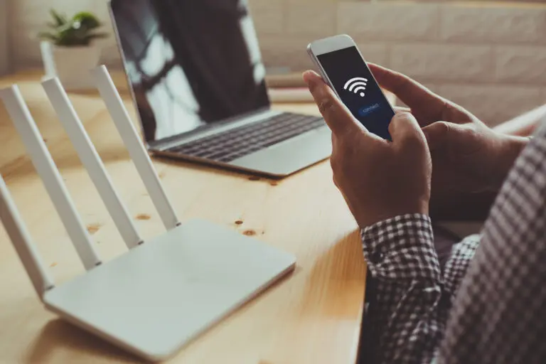 Closeup,Of,A,Wifi,Router,And,A,Man,Using,Smartphone