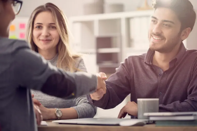 Young,Couple,Shaking,Hands,With,A,Female,Agent