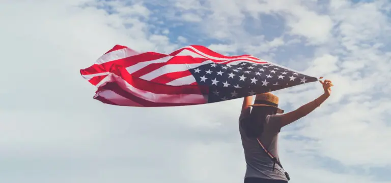 Young,Woman,Holding,American,Flag,On,Blue,Sky,Background,With