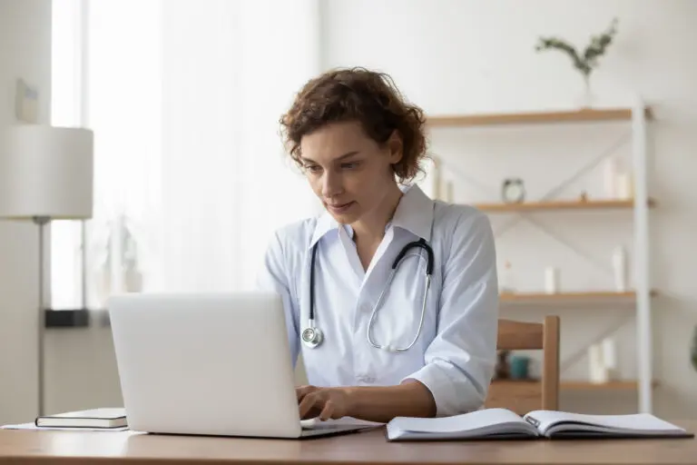Serious,Woman,Wearing,White,Uniform,With,Stethoscope,Working,On,Laptop,