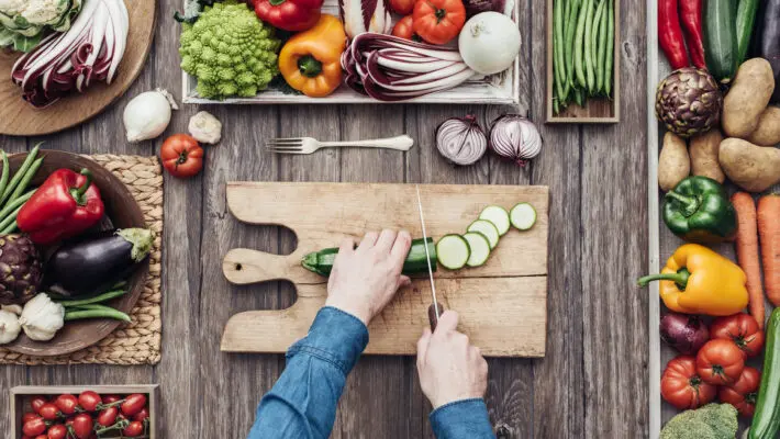 Man,Cooking,And,Slicing,Fresh,Vegetables,On,A,Rustic,Kitchen