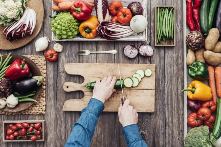 Man,Cooking,And,Slicing,Fresh,Vegetables,On,A,Rustic,Kitchen