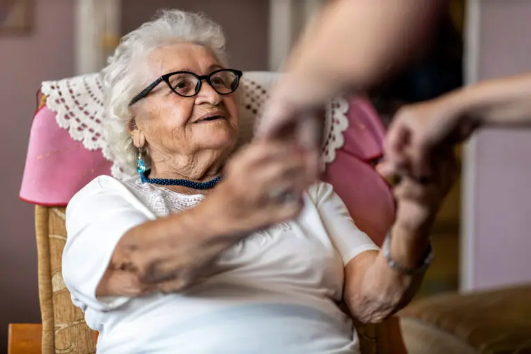 Female,Home,Carer,Supporting,Old,Woman,To,Stand,Up,From