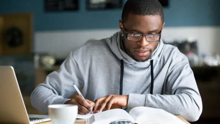 Focused,Millennial,African,American,Student,In,Glasses,Making,Notes,Writing