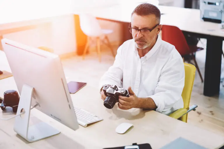 Male programmer 50 years old looking picture made by colleague a