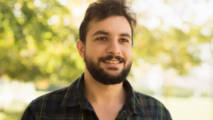 Bearded man in outdoors park. Smiling disheveled