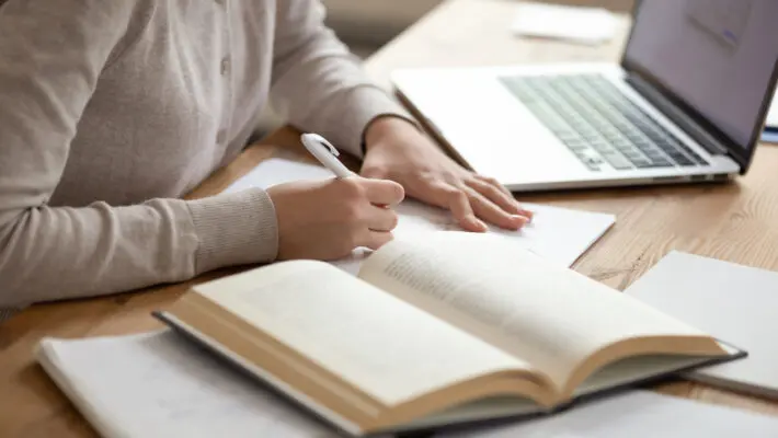 Close,Up,Female,Student,Sitting,At,Desk,,Writing,Down,Notes