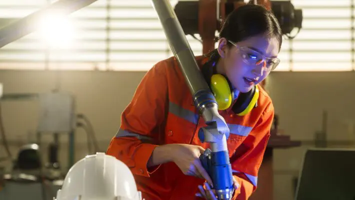 asian female engineer specialist with Measuring machine with a manipulator arm.Three-dimensional coordinate measurement. Check sizes. 3D check of the sizes of parts. CMM after machining process