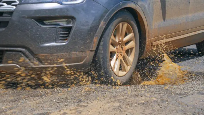 Close,Up:,Driving,Car,Hits,A,Pothole,In,Asphalt,Road