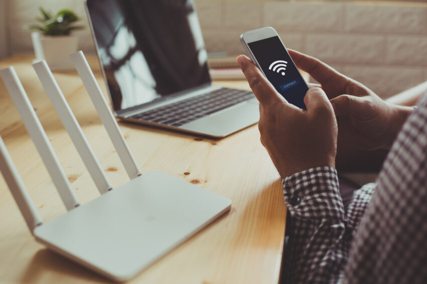 Closeup,Of,A,Wifi,Router,And,A,Man,Using,Smartphone