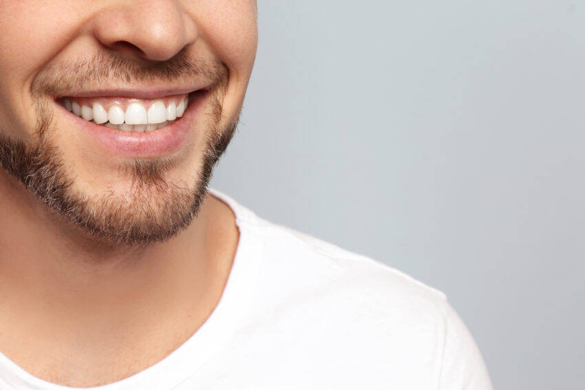 Young,Man,With,Beautiful,Smile,On,Grey,Background.,Teeth,Whitening