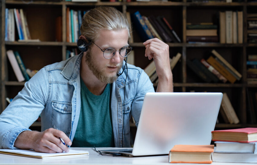 Focused,Young,Man,Student,Wear,Headset,Look,At,Laptop,Screen